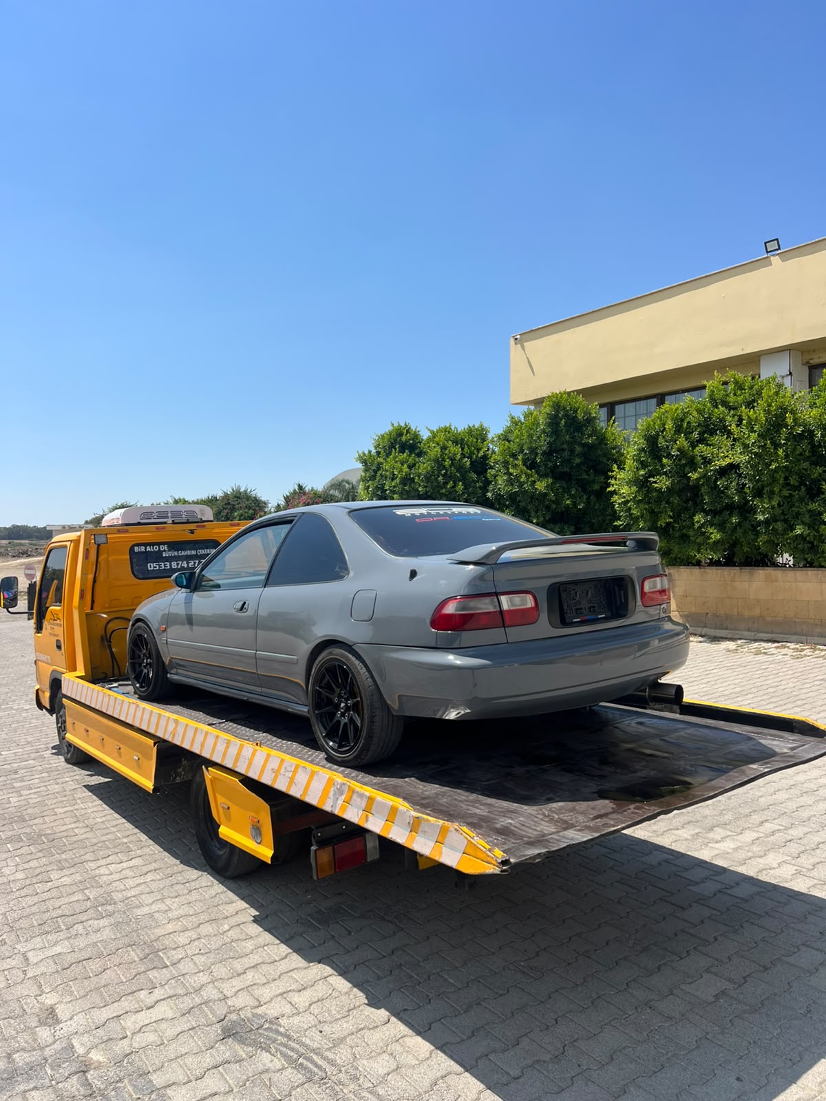 Gri otomobilin çekici üzerine güvenli yüklenmesi